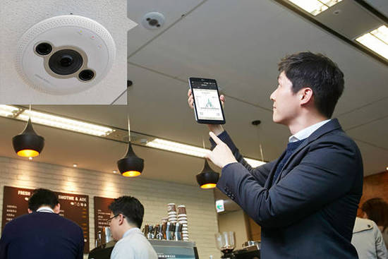 한 카페에서 LG CNS의 지능형 CCTV ‘스마트비전센서’가 분석한 실시간 고객 방문 정보를 스마트폰 앱을 통해 확인하고 있다. (사진 = LG CNS) 