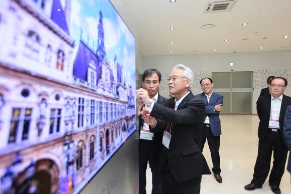 LG디스플레이 CTO 강인병 전무(왼쪽)가 Kaneka의 히로사쿠 나가노(Hirosaku NAGANO) 부사장(오른쪽)에게 55인치 월페이퍼 TV를 소개하고 있다.(사진=LGD) 