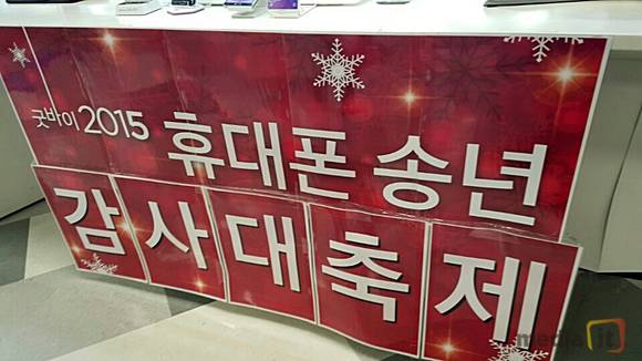 판매점 앞에 '2015 휴대폰 송년 감사대축제' 포스터가 붙어 있는 모습 