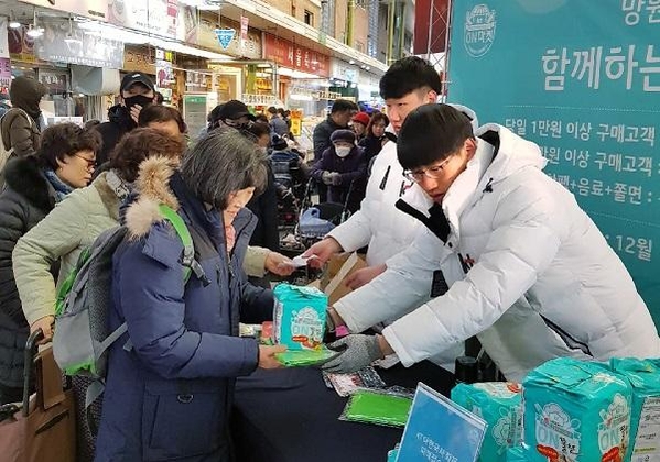 KT 임직원이 15일 서울 마포구 망원시장에서 열린 온마켓 행사에서 시장 방문객에게 장바구니와 온쫄면, 온음료 등을 나눠주고 있다. / KT 제공