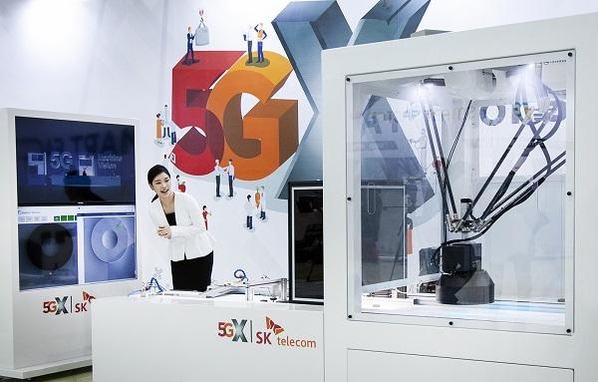 SK텔레콤 모델이 5G 스마트 유연생산 설비를 통해 소형IoT 기기가 만들어지는 과정을 지켜보고 있다. / SK텔레콤 제공
