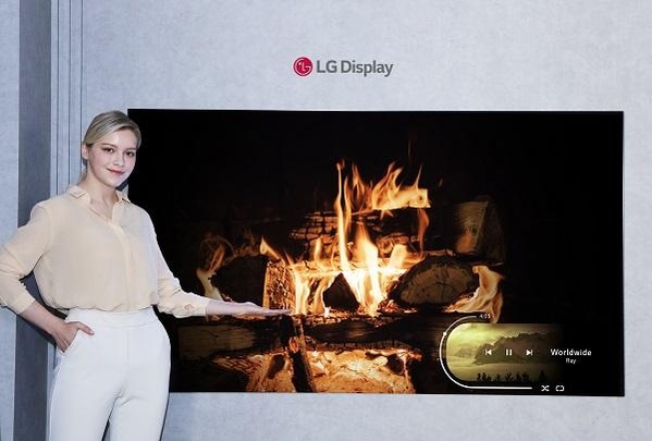 LG디스플레이 모델이 신규 OLED 소자가 적용된 77인치 차세대 OLED TV 패널을 소개하고 있다. / LG디스플레이