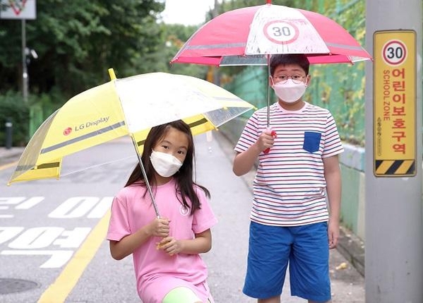 어린이들이 LG디스플레이가 준비한 '투명 안전 우산'을 쓰고 가는 모습 / LG디스플레이