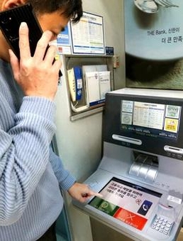 휴대폰 통화 도중 AI 이상행동탐지 ATM을 이용하자, 화면에 금융사고 예방 주의 문구가 나오는 모습. / 신한은행