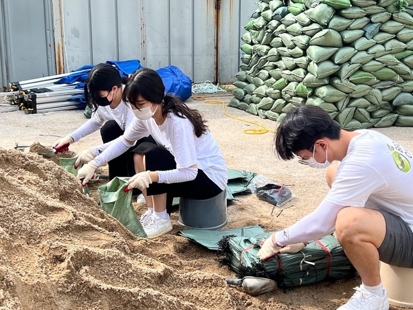 BBQ 대학생 봉사단 올리버스 단원들이 반포 종합운동장에서 물막이용 모래주머니를 제작하고 있다. / 제너시스BBQ