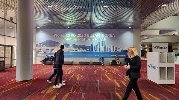 ‘2030 부산엑스포 유치 기원’ 대형 현수막이 게시된 CES 2023 행사장인 미국 라스베이거스 컨벤션 센터안에서 관람객들이 지나가고 있다. / SK이노베이션