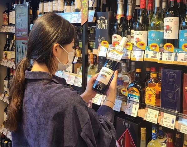 한 소비자가 이마트24 매장에서 와인을 살펴보고 있다. / 이마트24