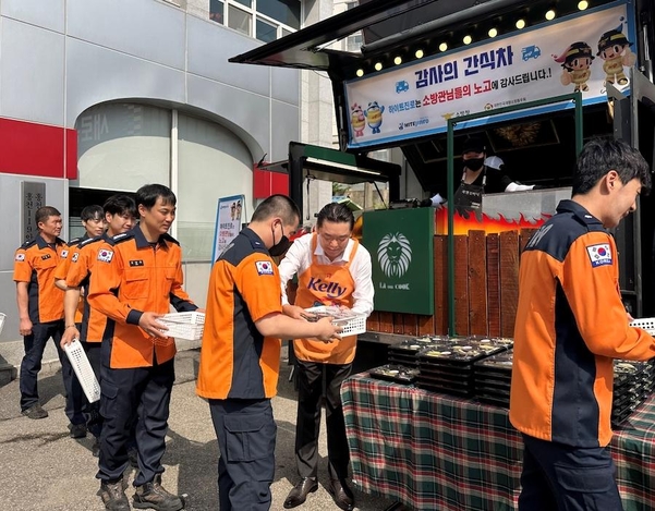 김인규 하이트진로 대표(오른쪽 두 번째)가 홍천소방서 소방공무원에게 간식과 선물을 직접 전달하고 있다. / 하이트진로