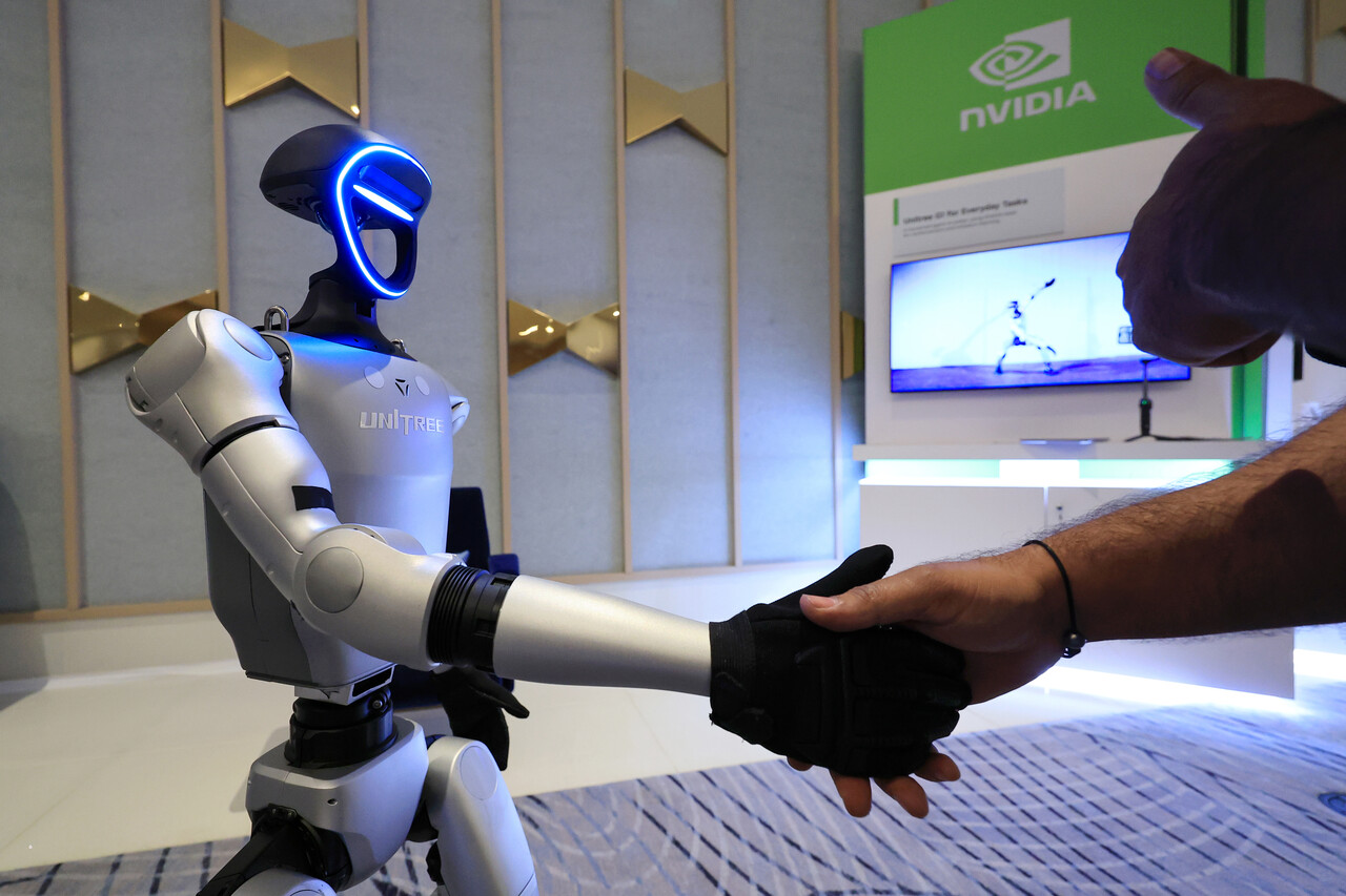 세계 최대 가전·정보기술(IT) 전시회 CES 2025 개막일인 7일(현지시간) 젠슨 황 엔비디아 최고경영자(CEO) 글로벌 기자간담회가 열린 미국 네바다주 라스베이거스 퐁텐블루 호텔에 마련된 엔비디아 전시관에서 휴머노이드 로봇 유니트리 G1이 관람객과 악수하고 있다. /뉴스1