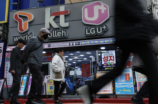 시민들이 3월 12일 서울의 한 휴대폰 매장 앞을 지나가고 있다. / 뉴스1
