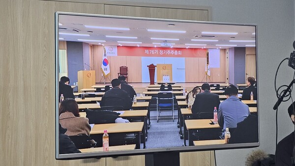 모니터를 통해 확인한 주총장 내부 공간. 2~3인용 테이블에 회사 임직원들로 보이는 주주들이 띄엄띄엄 착석해 자리를 차지하고 있다. 앞부분은 임원석이라고 미리 비워 놓았다. 마치 코로나 시국을 보는 듯한 분위기다./  손희동 기자 