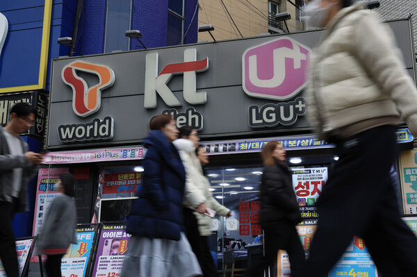 시민들이 3월 12일 서울의 한 휴대폰 매장 앞을 지나가고 있다. / 뉴스1