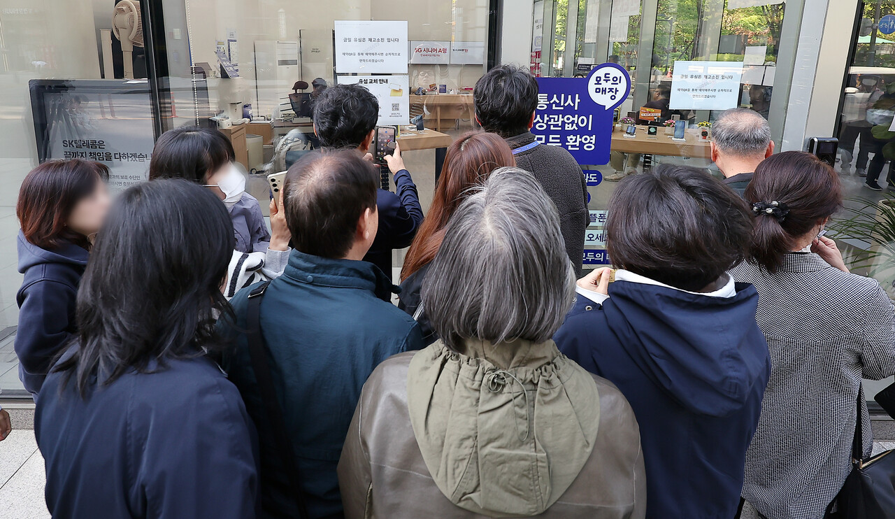 SK텔레콤 가입자 유심(USIM) 정보 해킹 사고 관련 유심 무료교체 서비스 이틀 째인 29일 오전 서울 종로구 T월드 직영 매장 앞에서 번호표를 받지 못한 고객들이 온라인 예약을 하고 있다./뉴스1