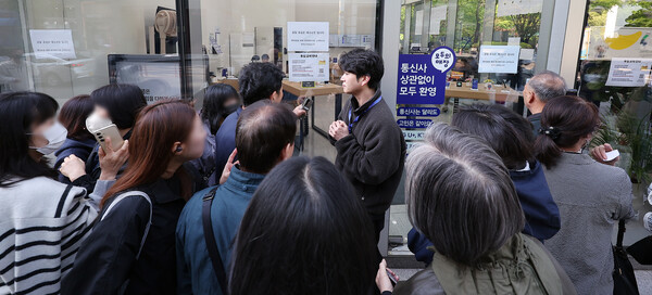 SK텔레콤 가입자 유심(USIM) 정보 해킹 사고 관련 유심 무료교체 서비스 이틀 째인 29일 오전 서울 종로구 T월드 직영 매장 앞에서 매장 관계자가 번호표를 받지 못한 고객들에게 온라인 예약을 안내하고 있다. / 뉴스1