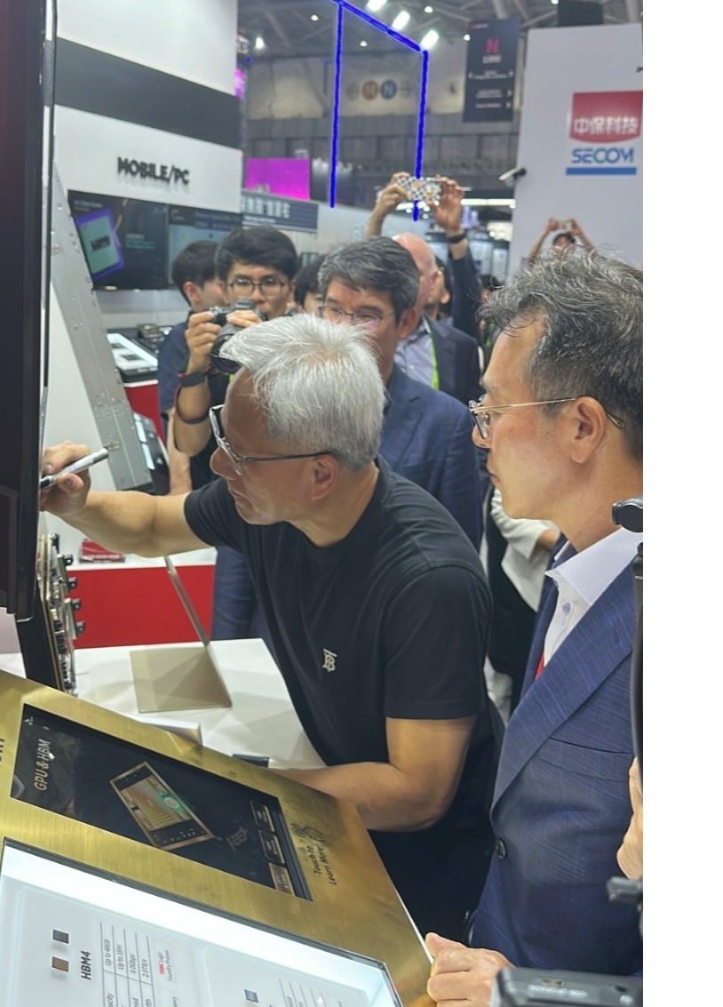 젠슨 황 엔비디아 CEO가 20일 오후 대만 타이베이 난강 전시관에서 개최된 '컴퓨텍스 2025'에서 SK하이닉스 부스를 찾아 전시된 HBM에 사인하고 있다. / 공동취재단