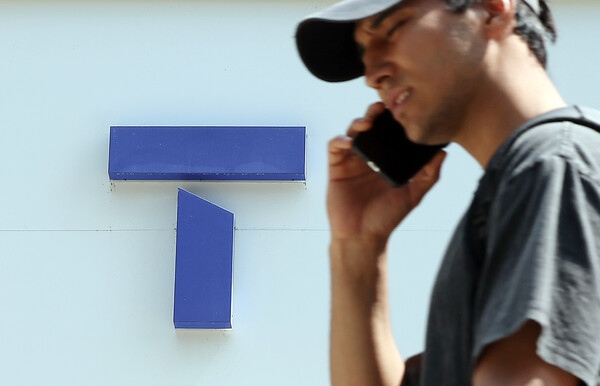 A citizen passes in front of a SKT store in downtown Seoul on June 23. / News 1