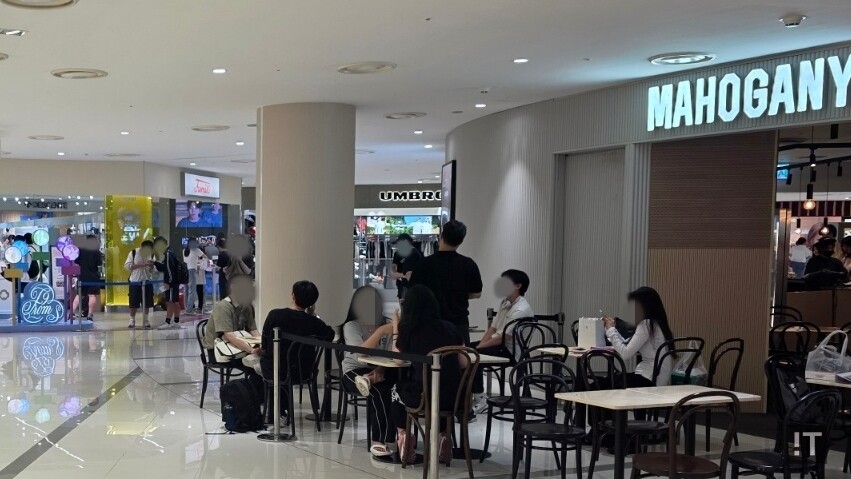 영등포 타임스퀘어 팝업스토어 인근 카페에 앉은 팬들이 구매한 물품을 정리하고 있다. / 변인호 기자