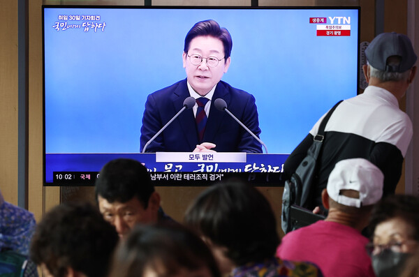 3일 오전 서울역 대합실에서 시민들이 이재명 대통령 ‘취임 한달’ 기자회견 생중계 영상을 시청하고 있다. /뉴스1