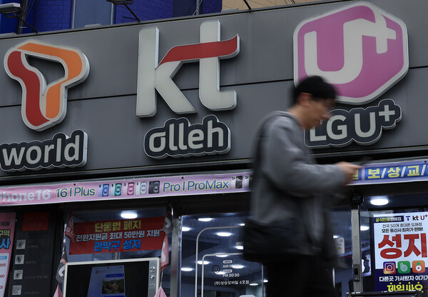 A citizen walks by in front of a mobile phone store in Seoul on March 12. / News 1