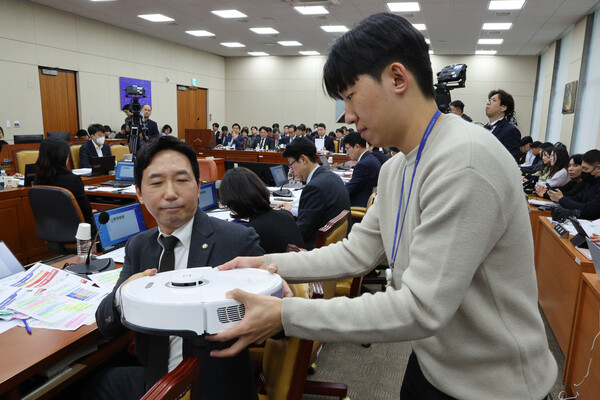 이정헌(왼쪽) 더불어민주당 의원이 10월 21일 서울 여의도 국회 과학기술정보방송통신위원회에서 열린 정보통신산업진흥원 등에 대한 국정감사에서 질의를 하기 위해 보좌진으로부터 로봇청소기를 건네받고 있다. / 뉴스1